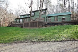 Une cabane à l’extérieur vert, dotée d’une terrasse en bois et de fondations en pierre.