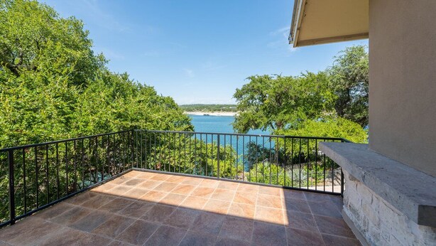 A balcony with a view of a body of water and surrounding greenery. - Waterfront Homes on Lake Travis (Spicewood)