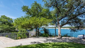 A coastal property with a paved walkway, trees, and a view of the sea. - Waterfront Homes on Lake Travis (Spicewood)