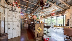 A rustic interior with a wooden bar area, a bear crossing sign, and a large window offering a view of the outdoors. - Waterfront Homes on Lake Travis (Spicewood)