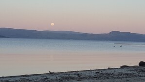 A calm lake with a visible moon in the sky and distant hills. - Lake front luxury at your door step (Ngongotaha)