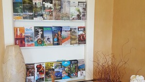 A bookshelf with travel brochures and a vase with flowers on a wooden dresser. - Lake front luxury at your door step (Ngongotaha)