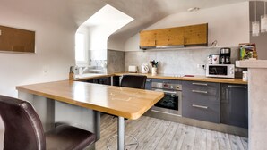 A modern kitchen with a wooden table, grey cabinets, and a built-in oven. - The Heart of Amboise, three-room apartment, two bedrooms in the city center (Amboise)
