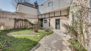 A courtyard with a stone pathway, a small garden, and a building with a green door and windows. - The Heart of Amboise, three-room apartment, two bedrooms in the city center (Amboise)