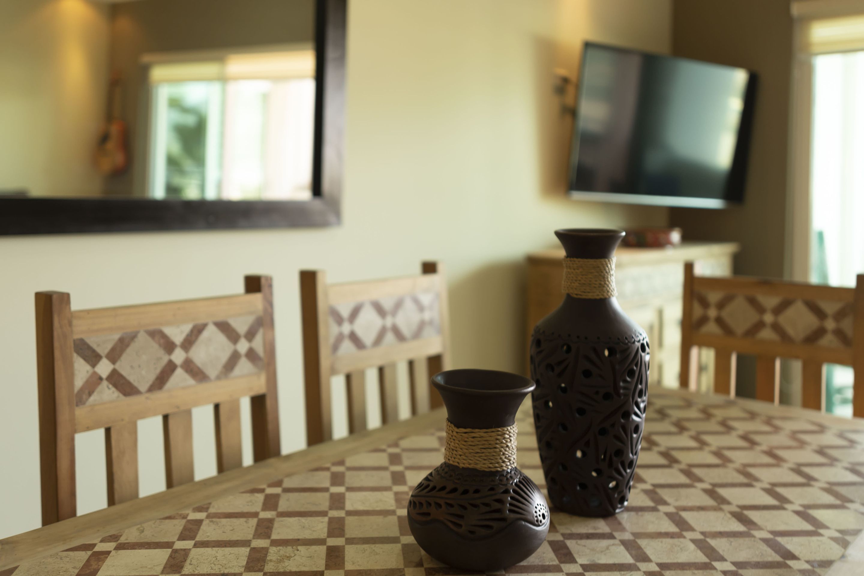 Une table à manger avec deux vases et un téléviseur en arrière-plan.