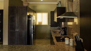 A modern kitchen with granite countertops, a built-in oven, and a stainless steel range hood.