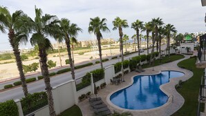 A swimming pool with a curved design, surrounded by palm trees and a well-maintained lawn.