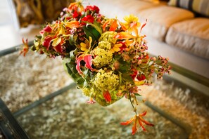 Een boeket bloemen in een glazen vaas op een glazen tafel.
