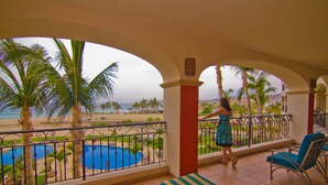 Un balcon avec vue sur une piscine, des palmiers et la plage.