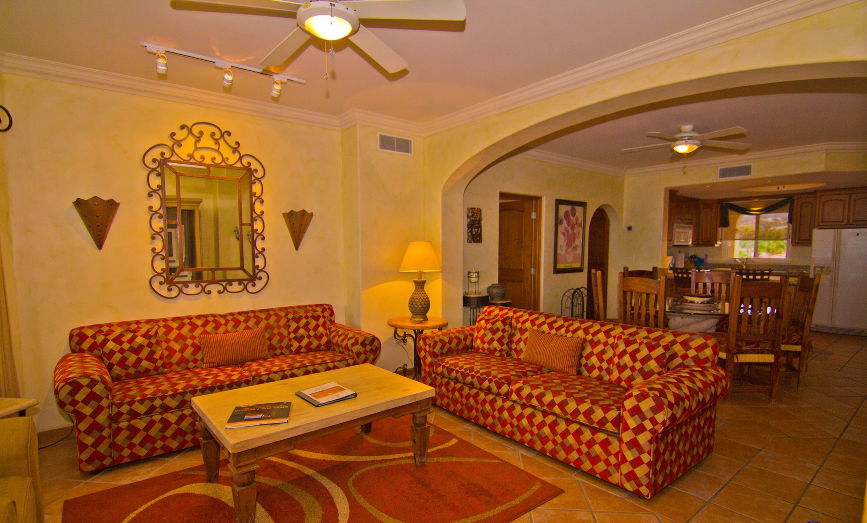 A living room with two patterned sofas, a coffee table, a floor lamp, and a ceiling fan.