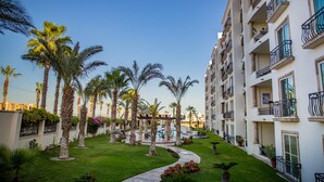 A hotel courtyard with palm trees, a central fountain, and a pool. - Puerta Cabos Village G207 2BR by Casago (Cabo San Lucas)
