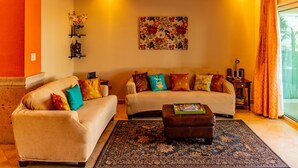 A living room with two sofas, a coffee table, and a large floral artwork on the wall. - Puerta Cabos Village G207 2BR by Casago (Cabo San Lucas)