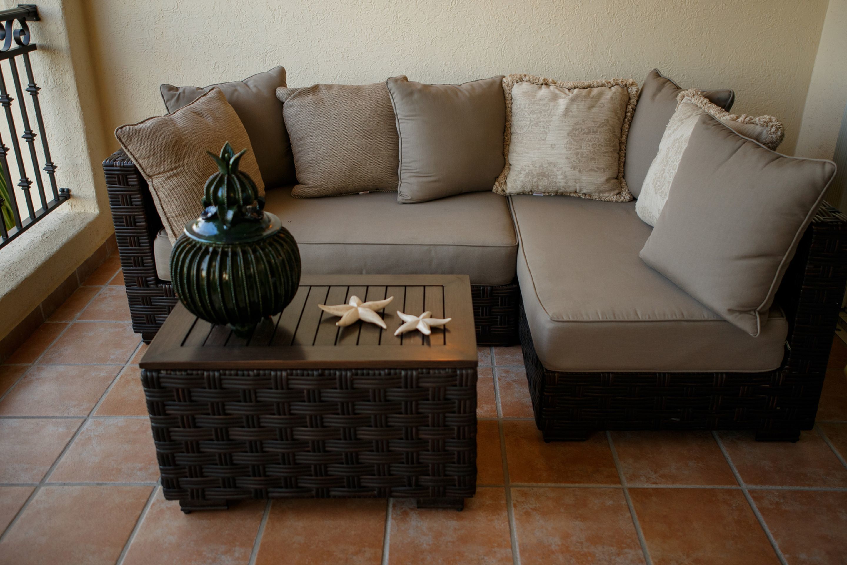 Ein modulares Sofa mit mehreren Kissen, ein gewebter Couchtisch und dekorative Seesterne.