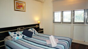 A hotel room with a bed, a bedside table with a lamp, a radio, and a framed picture on the wall. - 10 Tautog Street - Great Family space in central location (EXMOUTH)