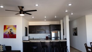 Una cocina moderna con armarios oscuros, un refrigerador de acero inoxidable y una barra con taburetes.