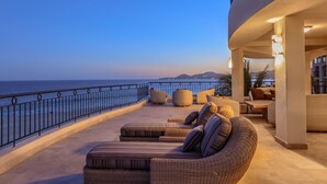 Ein Balkon mit Sitzgelegenheit im Freien, Blick auf das Meer und eine Gebäudefassade.