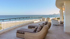 Ein Balkon mit Korbmöbeln mit Blick auf einen Strand und das Meer.