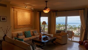 Un salón amplio con un conjunto de sofás, una mesa de centro y vistas al océano a través de ventanas grandes.
