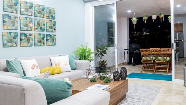A modern living room with a sofa, coffee table, and artwork on the wall. - Peninsula 103 2 BR by Casago (San José del Cabo)