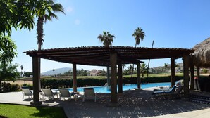 A thatched-roof gazebo with a pool and lounge chairs. - Peninsula 103 2 BR by Casago (San José del Cabo)