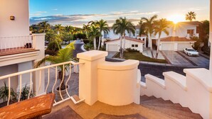 A residential area with a white house, a staircase, and a street with palm trees. - Villa De Oro 106 3 BR by Casago (Cabo San Lucas)
