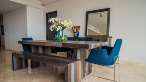A dining area with a wooden table, blue chairs, and a vase of flowers. - Cascadas de Pedregal 711 3 BR by Casago (Cabo San Lucas)