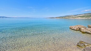 A clear view of a calm sea with rocky shores and distant hills under a blue sky. - Apartment Josipa by Interhome (Novi Vinodolski/Klenovica)