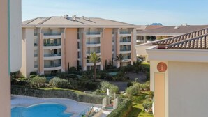 Un hôtel à plusieurs étages doté de balcons, d’une piscine et de jardins aménagés.
