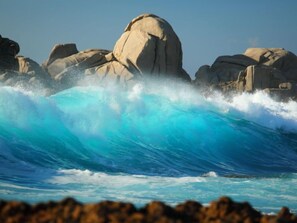 A large wave crashing against a rocky shoreline.