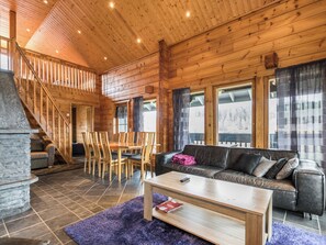 Un interior de madera con una escalera, un comedor y una sala de estar con un sofá y una mesa de centro.