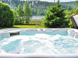 A hot tub with a view of a lake and forest.