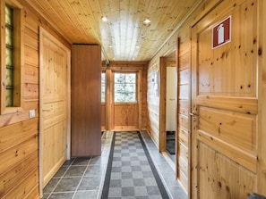 A wooden hallway with doors on both sides, a checkered rug on the floor, and a window at the end. - Nuppulanranta 14 by Interhome (Kuhmoinen)