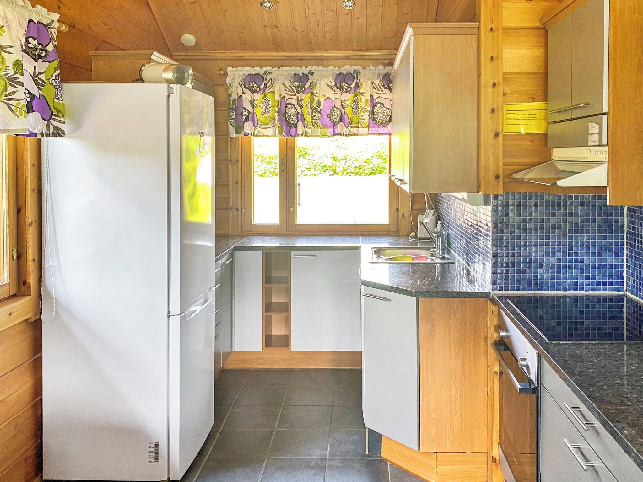 A compact kitchen with wooden cabinets, a white refrigerator, and a tiled backsplash.
