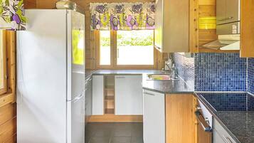 A compact kitchen with wooden cabinets, a white refrigerator, and a tiled backsplash.