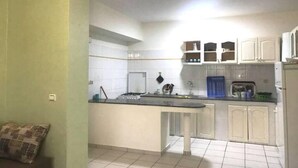 A compact kitchen with white cabinets, a central island, and a tiled floor. - Residence Cite Jardin 4065 (Martil)