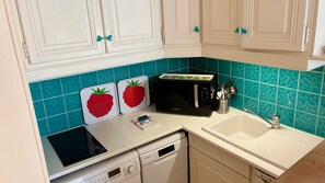 Une cuisine avec des meubles blancs, un four à micro-ondes, un évier et un lave-vaisselle.