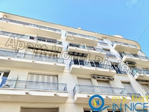 A multi-story building with balconies and a sign that reads "Apartments."