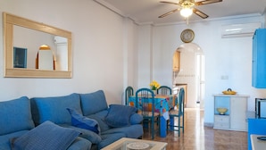 A living room with a sofa, a coffee table, and a dining area with chairs and a table.