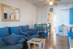 A living room with a sofa, a coffee table, and a dining area with chairs and a table.