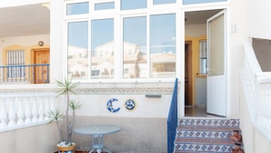 A balcony with a small table, potted plants, and a decorative wall with a moon and sun motif.