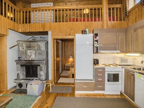A cozy cabin interior with a stone fireplace, a kitchen with modern appliances, and a wooden balcony. - Kanerva by Interhome (Juuka)