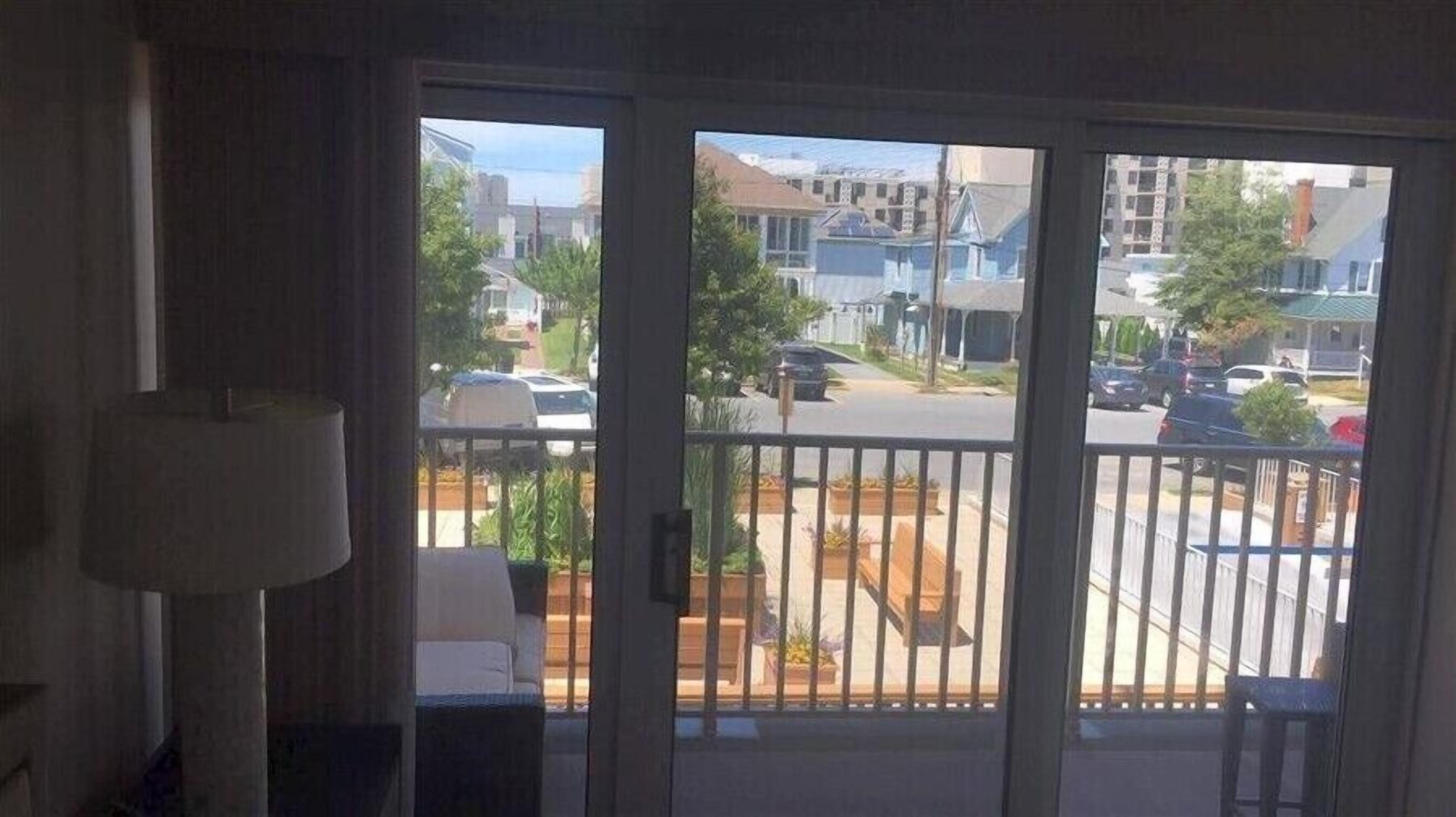 Ein Zimmer mit einer Schiebetür, die auf einen Balkon mit Blick auf eine Straße und Gebäude führt.