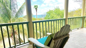 Ein überdachter Balkon mit Blick auf das Meer und Palmen.