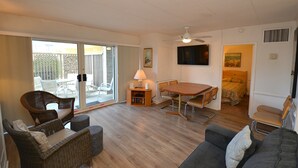 A room with a dining table, chairs, a sofa, a lamp, and a television. - 2 Bedrooms & 1 Bath in Rehoboth Beach, DE Ocean Block (Rehoboth Beach)