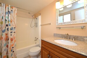 A bathroom with a shower, toilet, sink, and vanity.