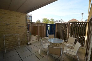 A patio with a table and chairs, a drying rack, and a view of neighboring buildings.