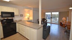 A kitchen with a microwave, stove, and white cabinets. - 2 Bedrooms & 1 Bath in Rehoboth Beach, DE Ocean Block (Rehoboth Beach)