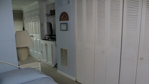Una camera da letto con un letto, una lampada da comodino, un armadio con ante a listelli e una cassettiera.