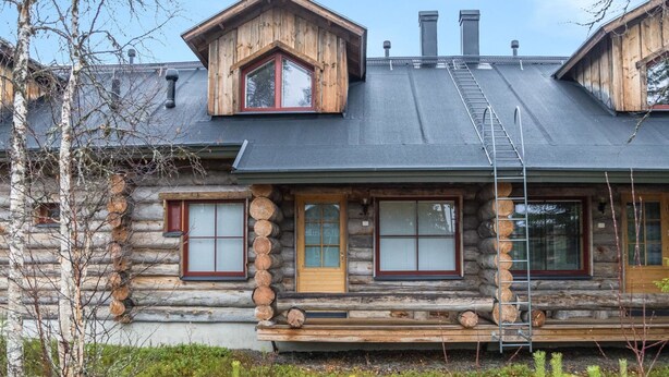 A log cabin with a sloped roof, multiple windows, and a wooden deck.