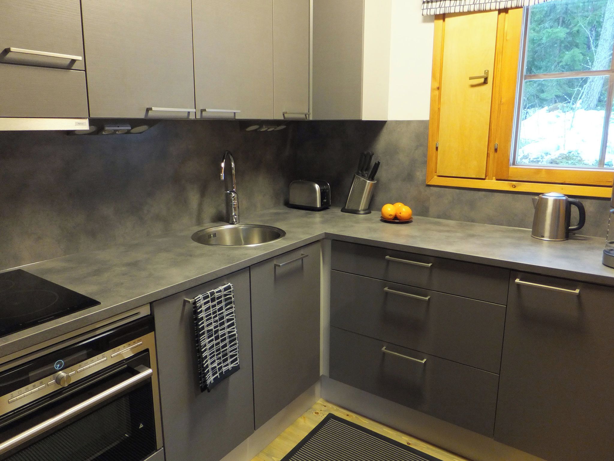 A modern kitchen with a built-in oven, a sink, a toaster, and a kettle.